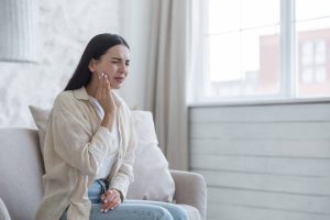 Woman sitting in pain due to tooth ache.